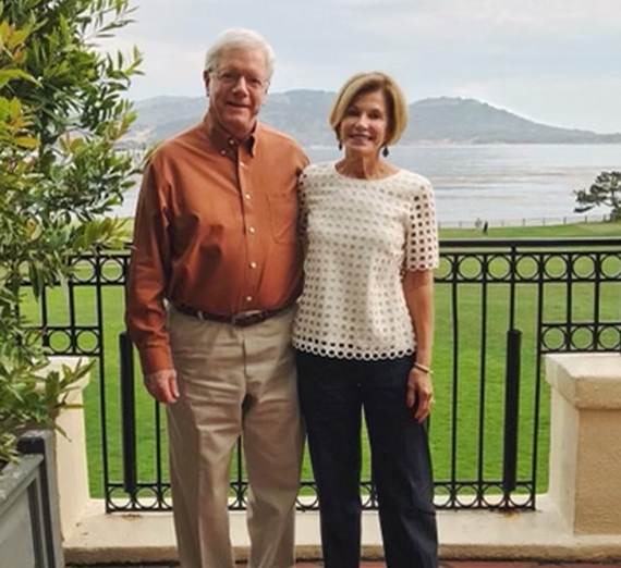 A woman in graduation cap and gown smiles at the camera